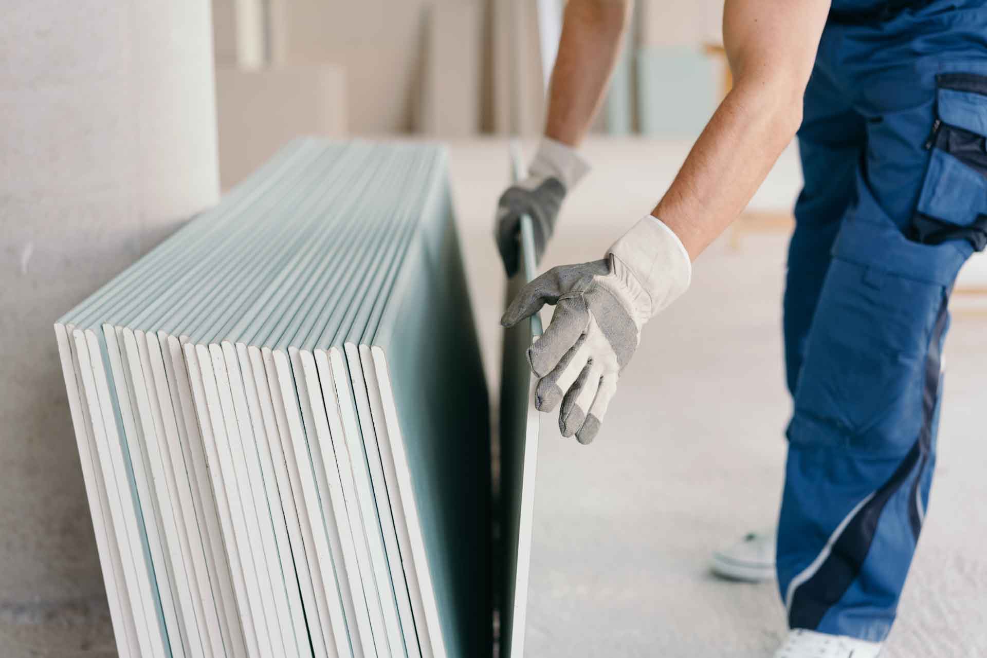 Handyman picking up a sheet of drywall