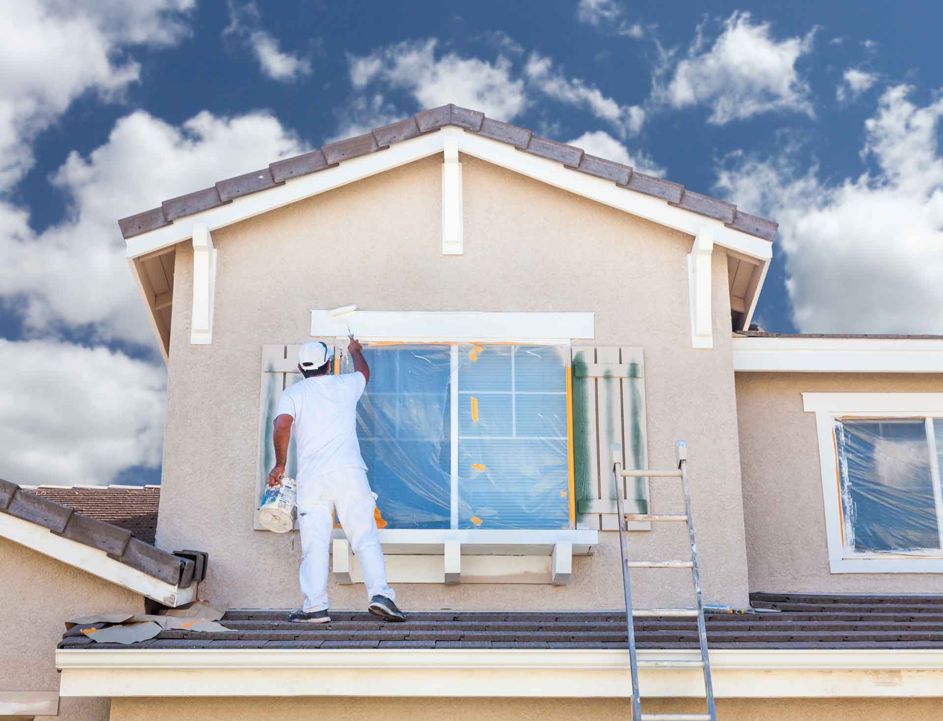 Exterior house painter works on details around window