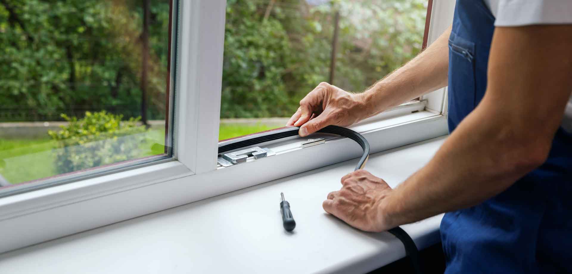 A handyman installs rubber seal on new window